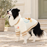 Seated Border Collie showing the WUKUISHOU chest lettering and oat-striped cuffs of a cream pet top. AI-edited lifestyle setting.